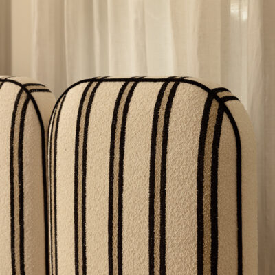 Two Willow upholstered chair backs with black vertical stripes sit in front of a sheer white curtain, creating a simple, modern aesthetic.
